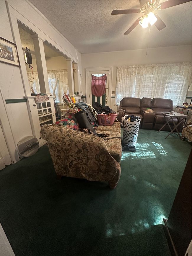 Carpeted living room with ceiling fan and a textured ceiling | Image 6