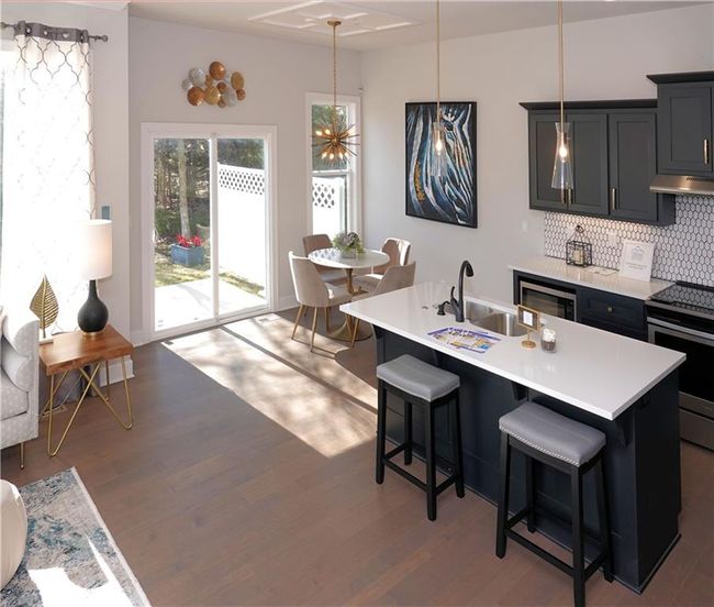 Kitchen featuring pendant lighting, stainless steel electric stove, light countertops, a kitchen island with sink, and under cabinet range hood | Image 20