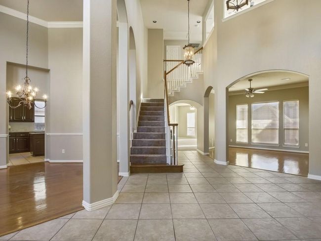 Foyer entrance featuring a high ceiling, a chandelier, stairs, crown molding, and healthy amount of natural light | Image 5