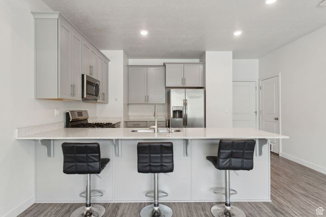 Kitchen featuring stainless steel appliances, LVP flooring, peninsula, with quartz countertops, and grey cabinetry | Image 9