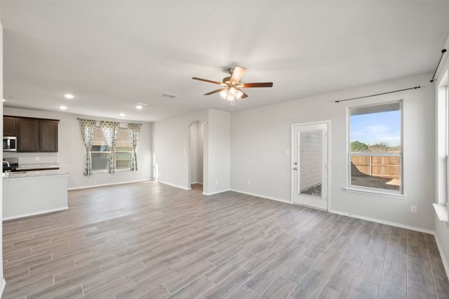 Unfurnished living room with visible vents, baseboards, a ceiling fan, arched walkways, and light wood-style floors | Image 34