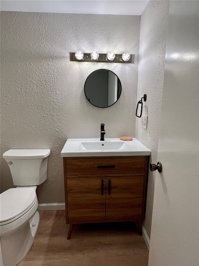 Half bathroom with vanity, toilet, wood finished floors, baseboards, and a textured wall | Image 19