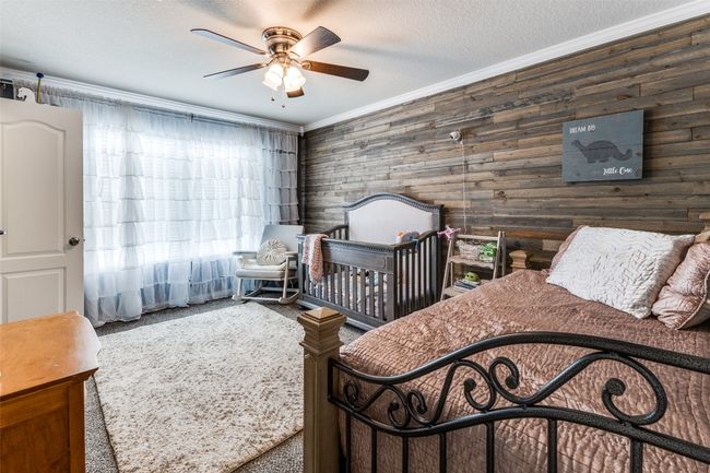 Carpeted bedroom with ornamental molding, wooden walls, a ceiling fan, and a textured ceiling | Image 25