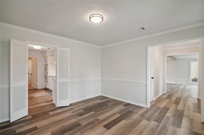 The bright, freshly painted dining room with modern luxury vinyl flooring and crown molding is located at the left side coming in and leads into the kitchen. | Image 11