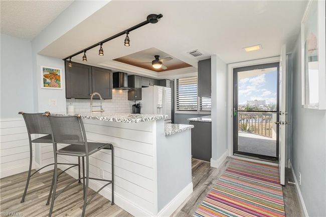 BREAKFAST BAR WITH SHIPLAP FRONT. SHIPLAP WAINSCOTING IN DINING AND LIVING AREA. TRACK LIGHTING. UNIT ENTRANCE SHOWN. | Image 7