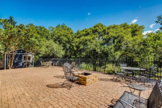 Sprawling back patio with fire pit overlooks greenbelt backyard setting and offers the perfect area for relaxation or entertaining! | Image 32