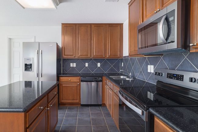 Kitchen featuring brown cabinetry, appliances with stainless steel finishes, and a sink | Image 13
