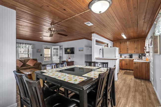 Dining space featuring wood ceiling, a ceiling fan, light wood-style floors, crown molding, and wood walls | Image 21