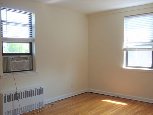 Bedroom with radiator, light wood finished floors, baseboards, and a healthy amount of sunlight | Image 16