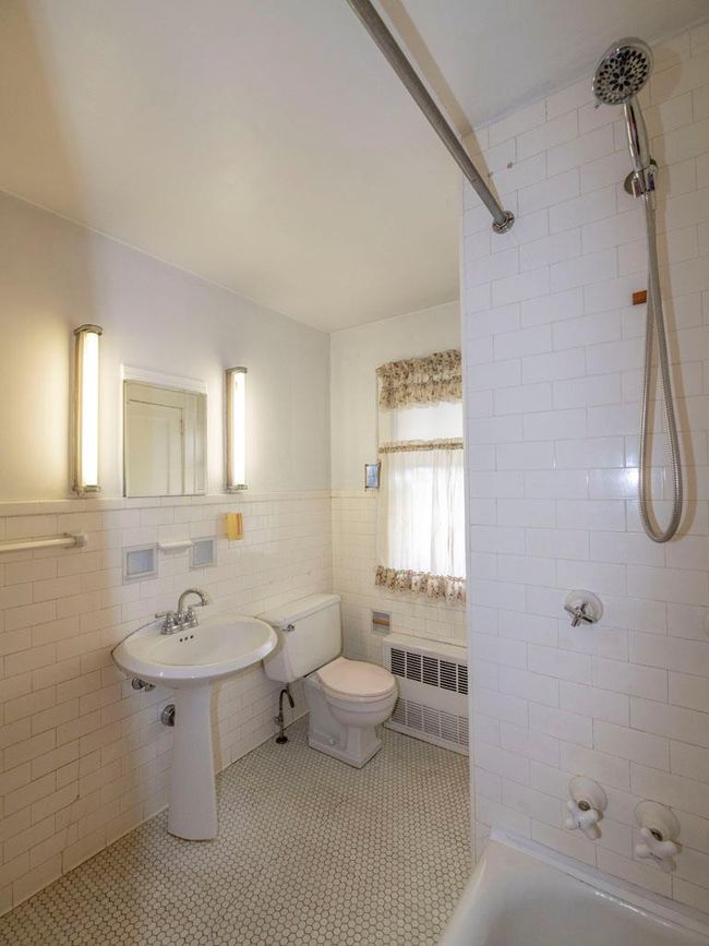 Bathroom with radiator heating unit, tile walls, tile patterned floors, shower / washtub combination, and a wainscoted wall | Image 22