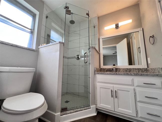 Bathroom featuring toilet, hardwood / wood-style floors, a shower with door, and vanity | Image 16