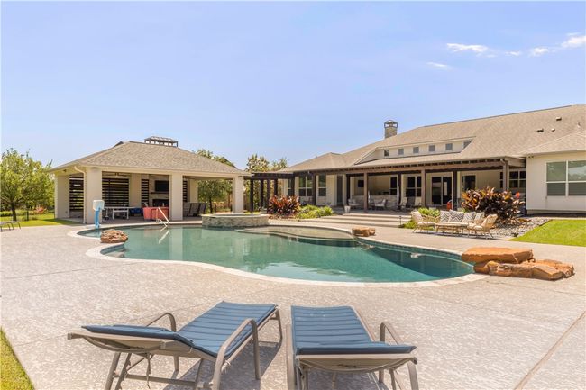 View of pool with a patio area and a pool with connected hot tub | Image 20