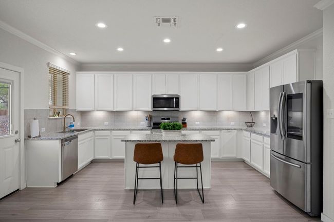 Kitchen with a kitchen breakfast bar, stainless steel appliances, ornamental molding, a kitchen island, and a sink | Image 4