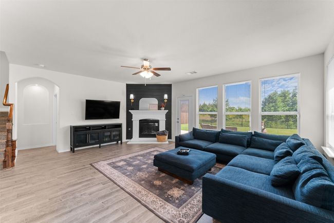 Living room featuring arched walkways, ceiling fan, light wood-style floors, and a glass covered fireplace | Image 12