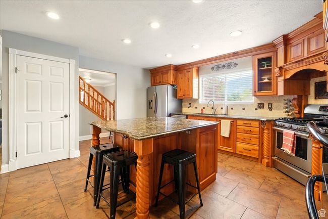 Kitchen with appliances with stainless steel finishes, a breakfast bar, tasteful backsplash, recessed lighting, and a center island | Image 23