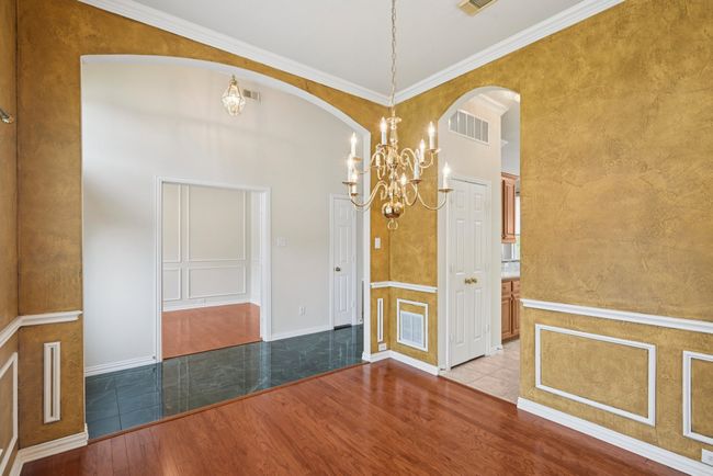 Spare room featuring wood finished floors, crown molding, a chandelier, and a high ceiling | Image 9