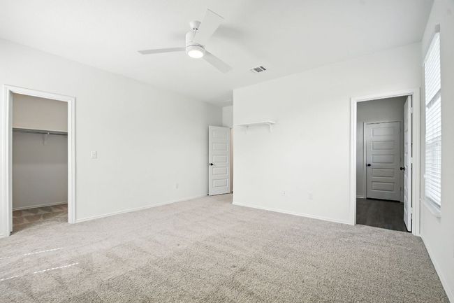 Unfurnished bedroom with carpet, a spacious closet, and a ceiling fan | Image 18
