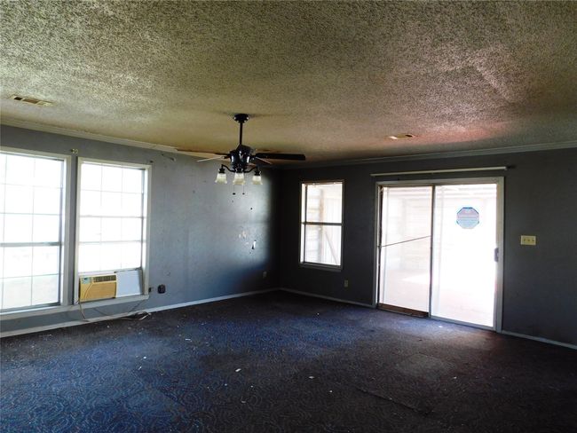 Carpeted spare room with ornamental molding, a textured ceiling, cooling unit, and a healthy amount of sunlight | Image 15