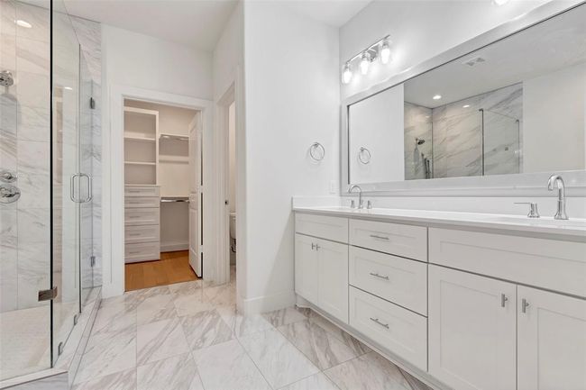 The primary bathroom boasts double sinks with a quartz countertop, ample drawers for storage, and a large rectangular mirror above the sinks. | Image 17