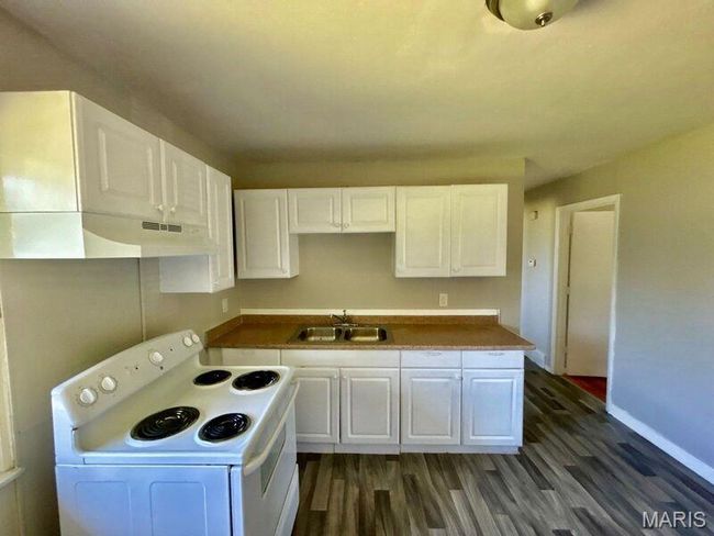 Kitchen with electric range, a sink, under cabinet range hood, dark wood-style flooring, and white cabinetry | Image 9