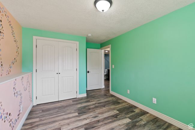 Unfurnished bedroom featuring a textured ceiling, wood finished floors, baseboards, and a closet | Image 22