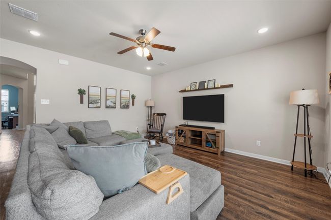 Living area featuring arched walkways, ceiling fan, dark wood-style flooring, and recessed lighting | Image 4