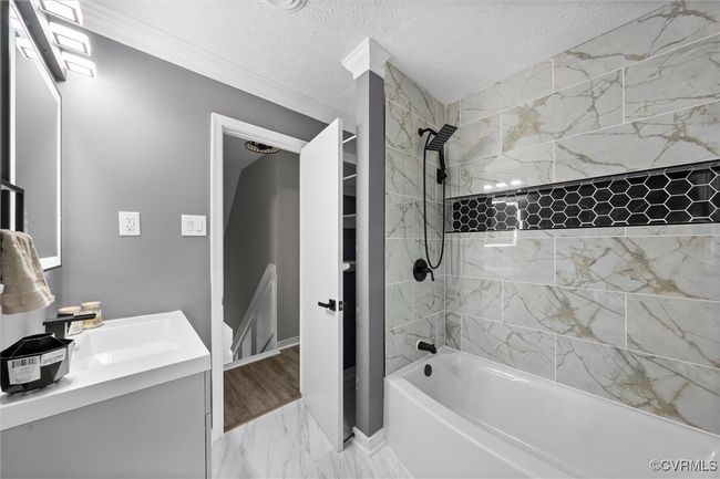 Full Bathroom with extured ceiling, shower / bathtub combination, vanity, and marble finish floors | Image 23