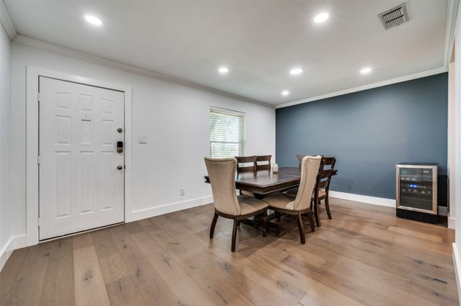 Dining area featuring wood finished floors, wine cooler, ornamental molding, and recessed lighting | Image 4