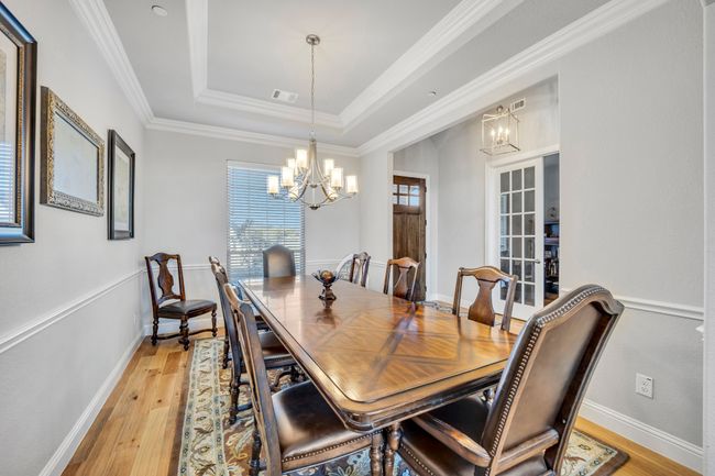 Dining space with a chandelier, light wood-type flooring, ornamental molding, and a tray ceiling | Image 5