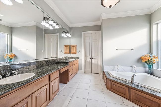 Enter into your Primary Bathroom that features his/her vanities with make up knee space, a standing shower & tub! Custom walk in closet is straight ahead! | Image 18