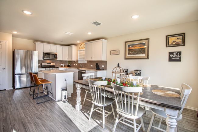 Kitchen with appliances with stainless steel finishes, a center island, white cabinetry, a kitchen bar, and recessed lighting | Image 11