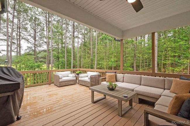 Deck featuring an outdoor hangout area, a ceiling fan, grilling area, and a wooded view | Image 45