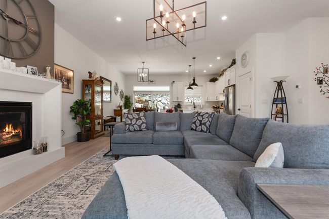 Living room featuring a chandelier, light wood-type flooring, a glass covered fireplace, and recessed lighting | Image 7