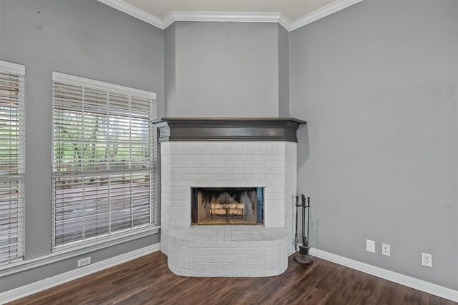 Detailed view of wood finished floors, ornamental molding, and a brick fireplace | Image 5