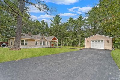 Ranch-style home with a garage, a front lawn, and an outbuilding | Image 2