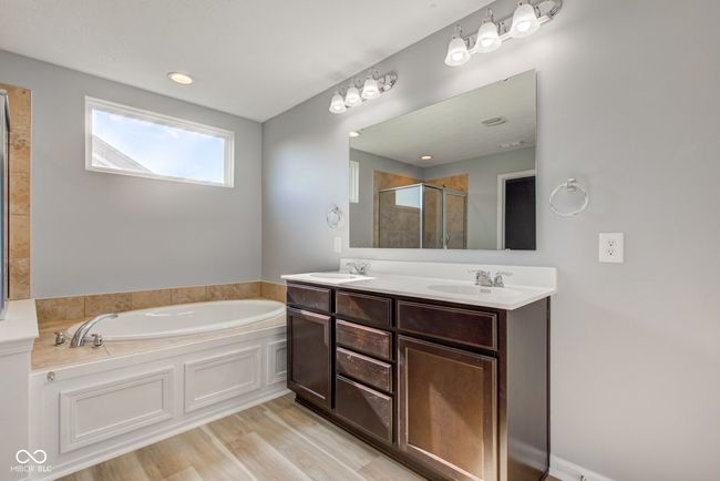 full bath featuring a bath, a shower stall, double vanity, and wood finished floors | Image 33