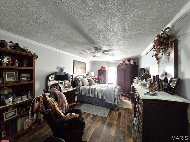 Bedroom featuring crown molding, dark wood-type flooring, a textured ceiling, and a ceiling fan | Image 10