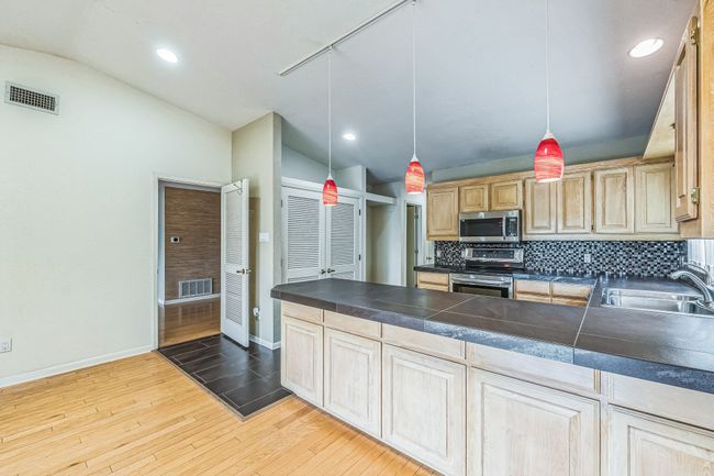 Kitchen with stainless steel appliances, a sink, baseboards, visible vents, and lofted ceiling | Image 13
