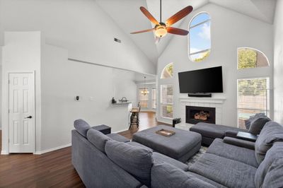 Living room featuring dark hardwood / wood-style flooring, a tile fireplace, ceiling fan, and high vaulted ceiling | Image 1