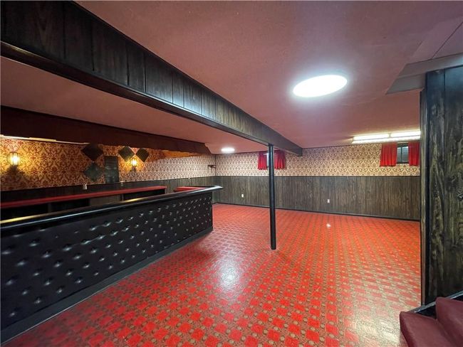 Bar with a community bar, wood walls, a wainscoted wall, wallpapered walls, and tile patterned floors | Image 26
