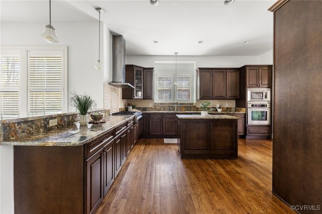 10' Ceilings, Surround sound, Island with storage, Kitchen Aid 5 burner gas range, Kitchen aid wall oven, Whirpool wall microwave, Kitchen aid stainless steel refrigerator and dishwasher, Granite countertops, Recessed and pendant lighting, Double bowl stainless sink, corner pantry, decorative tile behind the range, tile backsplash, bar seating. | Image 13