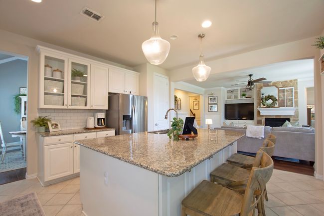 Kitchen with ceiling fan, a sink, stainless steel fridge with ice dispenser, light tile patterned floors, and visible vents | Image 10