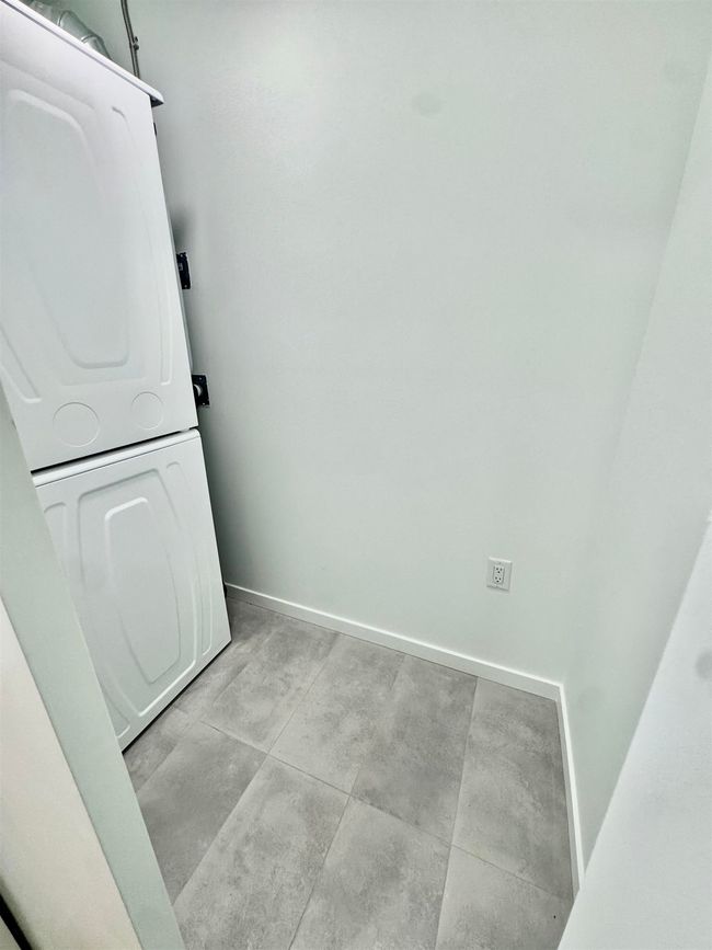 Clothes washing area featuring laundry area, stacked washer / drying machine, and baseboards | Image 18