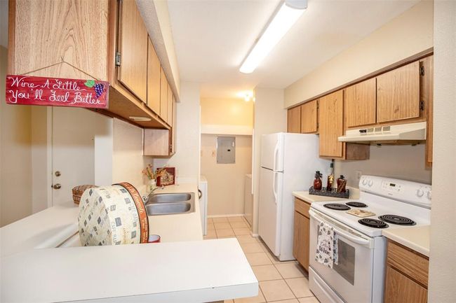 The kitchen is a warm and functional space featuring white appliances that contrast beautifully with rich wood like cabinetry. | Image 16