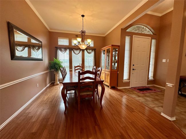 Dining area with an inviting chandelier, crown molding, baseboards, and wood finished floors | Image 13