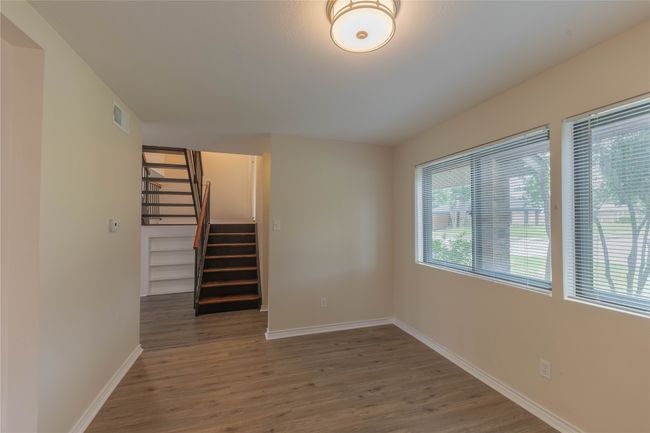 Spare room featuring wood finished floors, baseboards, and stairway | Image 11