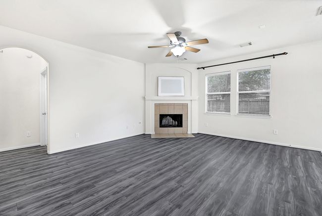 Spacious living room with updated flooring, cozy fireplace, and large windows. | Image 13