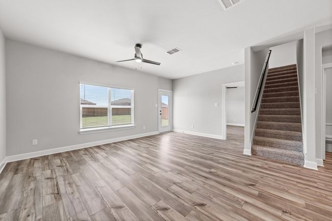 Unfurnished living room featuring stairway, visible vents, light wood finished floors, and a ceiling fan | Image 16