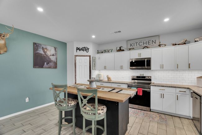 Kitchen featuring appliances with stainless steel finishes, wooden counters, backsplash, white cabinets, and recessed lighting | Image 6