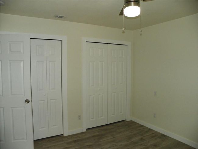 Unfurnished bedroom with multiple closets, dark wood finished floors, and ceiling fan | Image 17